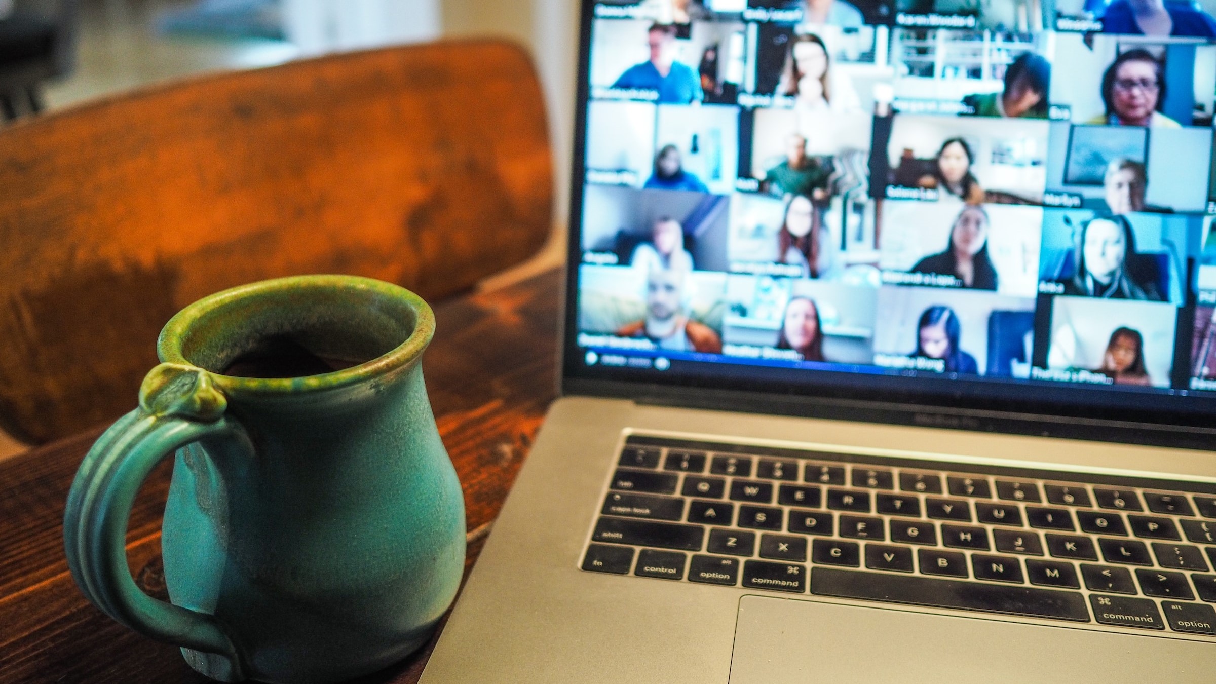 computer with coffee cup at the side, online meeting in progress on the screen